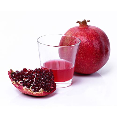 Freshly squeezed pomegranate juice in a glass next to a halved pomegranate